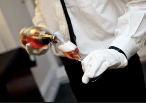 Butler trainee pouring champagne with precision in a luxury service environment