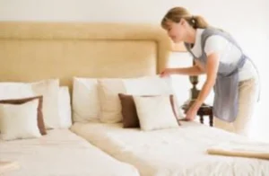 professional housekeeper making bed in private household bedroom