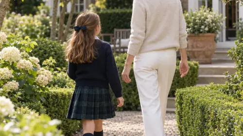 Attentive nanny walking with a child in a London garden